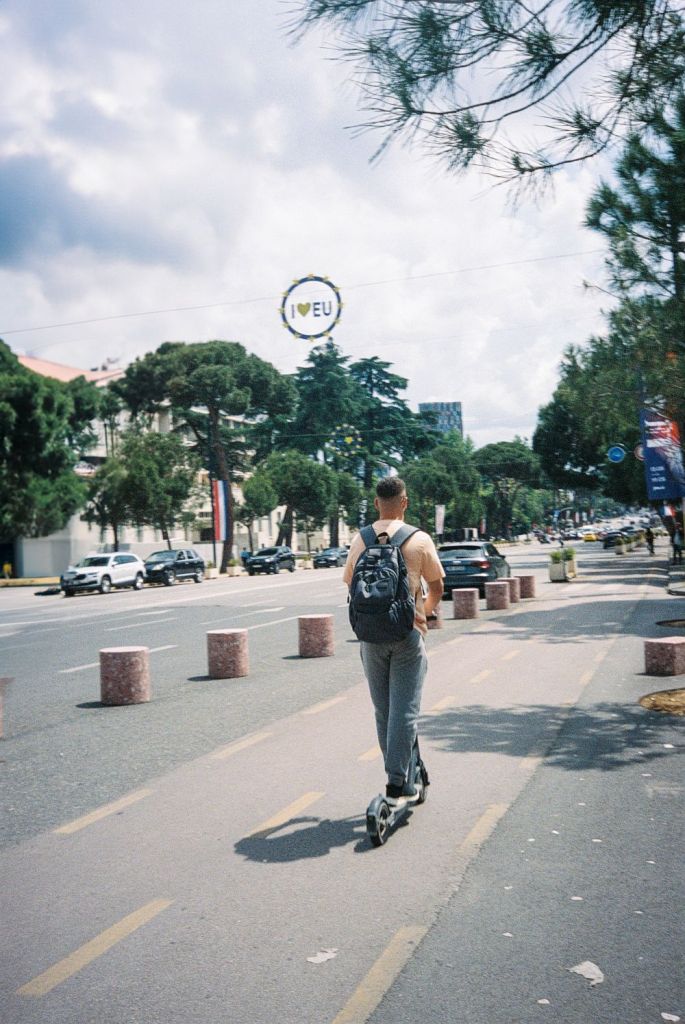 Mann auf einem Roller die Straße entlang fahrend.